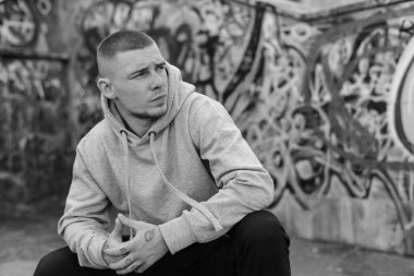 Açık renk spor ceketli, kapüşonlu bir kabadayı. Siyah beyaz fotoğraf. BW