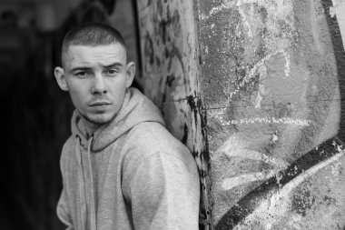 Açık renk spor ceketli, kapüşonlu bir kabadayı. Siyah beyaz fotoğraf. BW