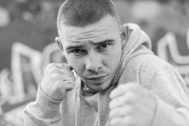 Açık renk spor ceketli, kapüşonlu bir kabadayı. Siyah beyaz fotoğraf. BW