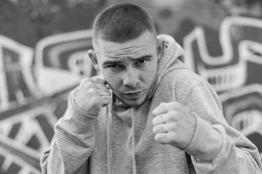 Açık renk spor ceketli, kapüşonlu bir kabadayı. Siyah beyaz fotoğraf. BW