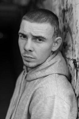 Açık renk spor ceketli, kapüşonlu bir kabadayı. Siyah beyaz fotoğraf. BW