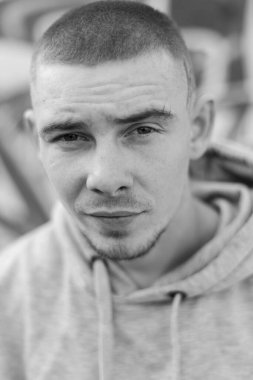 Açık renk spor ceketli, kapüşonlu bir kabadayı. Siyah beyaz fotoğraf. BW