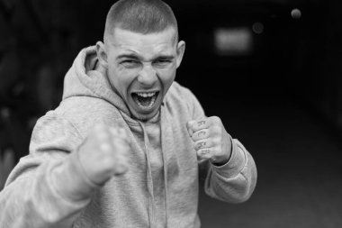 Açık renk spor ceketli, kapüşonlu bir kabadayı. Siyah beyaz fotoğraf. BW