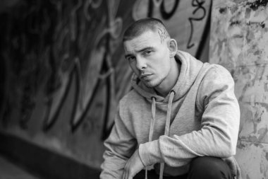 Açık renk spor ceketli, kapüşonlu bir kabadayı. Siyah beyaz fotoğraf. BW