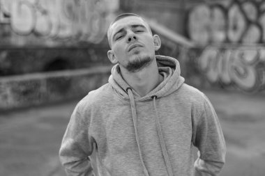 Açık renk spor ceketli, kapüşonlu bir kabadayı. Siyah beyaz fotoğraf. BW