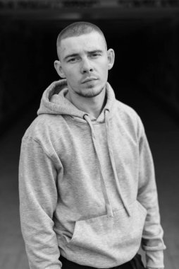 Açık renk spor ceketli, kapüşonlu bir kabadayı. Siyah beyaz fotoğraf. BW