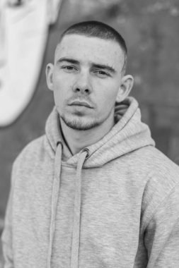 Açık renk spor ceketli, kapüşonlu bir kabadayı. Siyah beyaz fotoğraf. BW