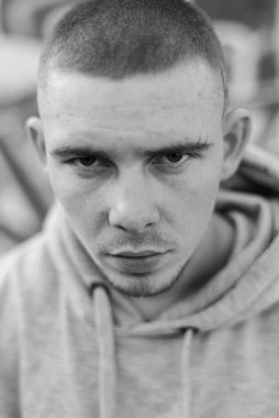 Açık renk spor ceketli, kapüşonlu bir kabadayı. Siyah beyaz fotoğraf. BW