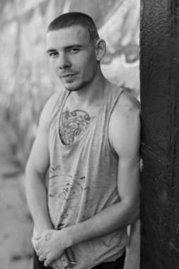 Duvarında grafiti olan spor tişörtlü bir kabadayı. Siyah beyaz fotoğraf. BW