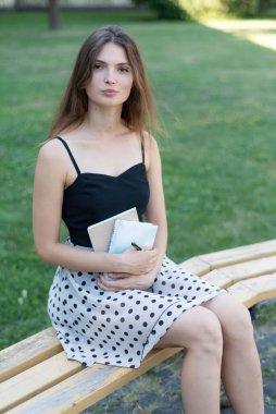 Üniversitenin yanındaki bankta elinde kitap ve defter olan kız öğrenci. Kyiv. Ukrayna