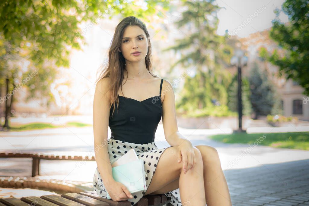 Girl student with a book and a notebook on a bench near the university. Kyiv. Ukraine