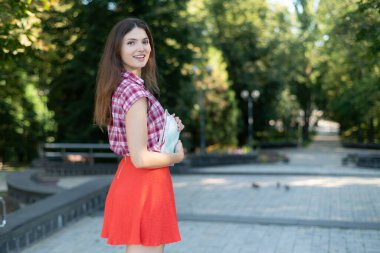 Kırmızı etekli ve ekose gömlekli kız öğrenci.