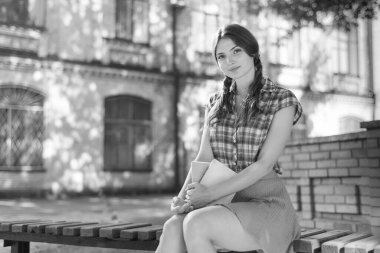 Bankta genç bir kız öğrenci. Siyah beyaz fotoğraf. BW