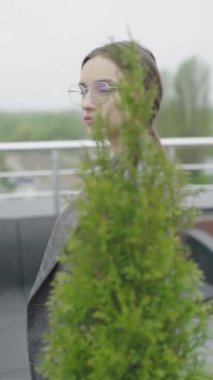 Dikey video. Gözlüklü ve gri takım elbiseli güzel bir kız. Yavaş çekim