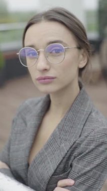 Dikey video. Gözlüklü ve gri takım elbiseli güzel bir kız. Yavaş çekim