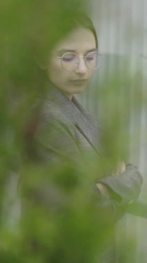 Dikey video. Gözlüklü ve gri takım elbiseli güzel bir kız. Yavaş çekim