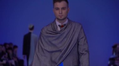 Moda gösterisi. Erkek manken podyumda yürüyor..