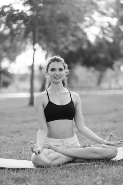 Menina fazendo ioga no parque durante o dia. Foto em preto e branco. BW — Fotografia de Stock