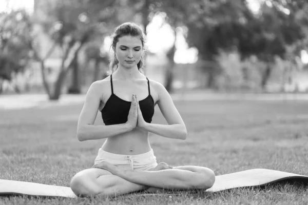 Mädchen machen tagsüber Yoga im Park. Schwarz-Weiß-Foto. BW — Stockfoto