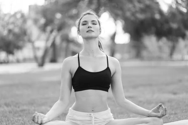 Girl doing yoga in the park during the day. Black and white photo. BW — Stock Photo, Image