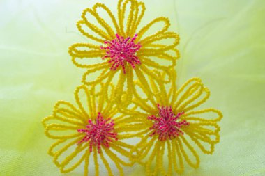 Üç sarı boncuklu çiçek pembe bir kalp, sarı bir arka plan bulanık.