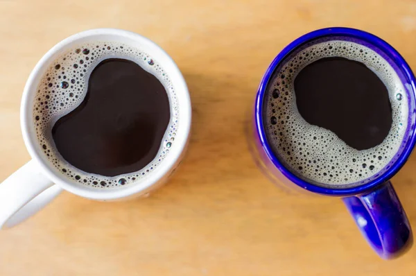 Two cups of coffee top view. Latte in a white mug. Black coffee in a blue mug. Good morning. Breakfast in bed.