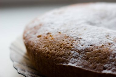 Koyu bir tabakta, yakın plan bir turta. Şekerli pandispanya..