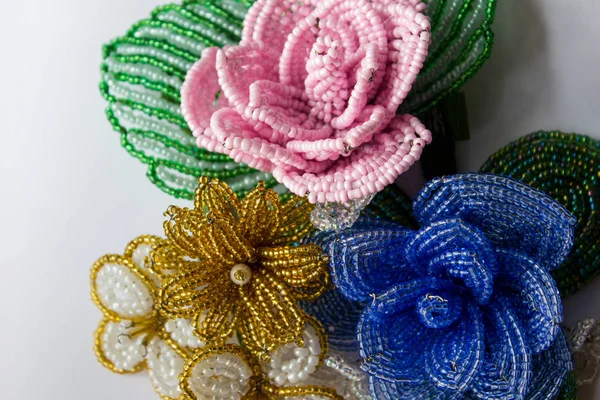 Beaded flowers on a white background. Blue bead flower, pink bead flower, yellow bead flower. Flowers from beads. Three flower from beads on a white background.