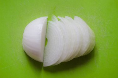 Yeşil arka planda dilimlenmiş soğan. Soğan kafa. Beyaz soğan. Mutfak geçmişi. Sebzeli yeşil arka plan. Üst görünüm, boşluk kopyala