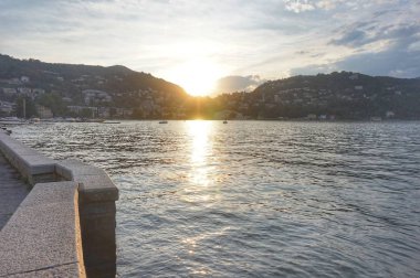 Güneş dağın üzerinden batıyor. Como şehrinde Como Gölü'nde gün batımı.