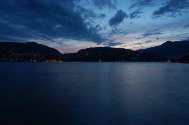 Güneş dağın üzerinden batıyor. Como şehrinde Como Gölü'nde gün batımı.