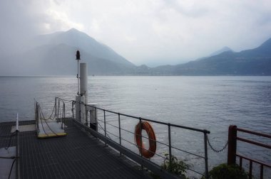 Güneş gök gürültüsü bulutlarının arasından kırılır. Como Gölü üzerindeki iskeleden manzara.