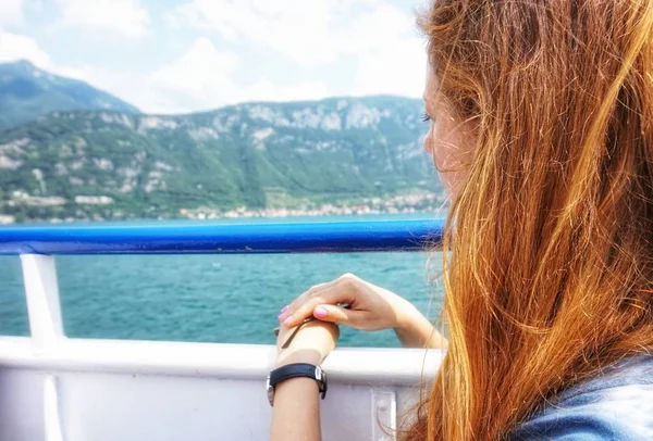 Kızıl saçlı kız yüzen geminin kenarında oturuyor..