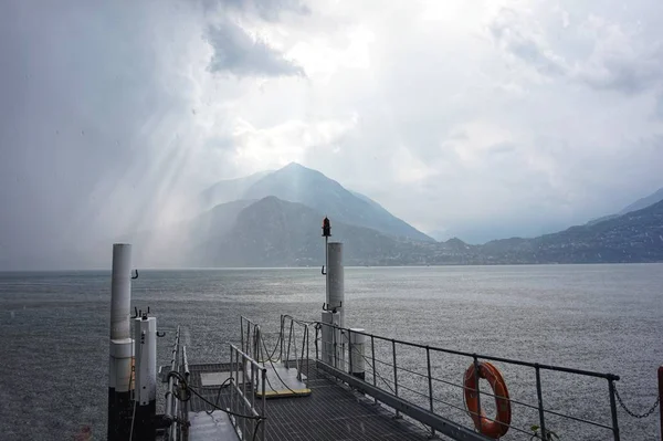 The sun breaks through the thunderclouds. View from the pier on Lake Como.