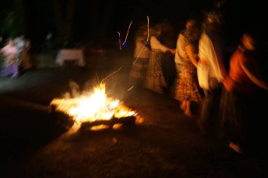İnsanlar Ivan Kupala şöleninde ateşin etrafında dans ediyorlar. Antik Slavonik geleneği.
