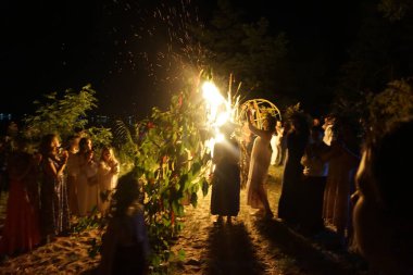 Çelenkli kızlar Ivan Kupala 'nın tatilinde şenlik ateşinin etrafında dans ediyorlar. Yaşayan putperest geleneği.