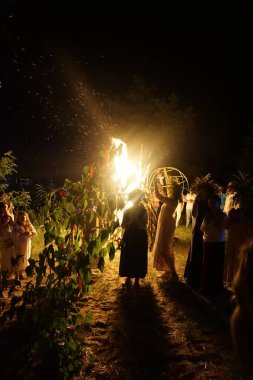 Çelenkli kızlar Ivan Kupala 'nın tatilinde şenlik ateşinin etrafında dans ediyorlar. Yaşayan putperest geleneği.