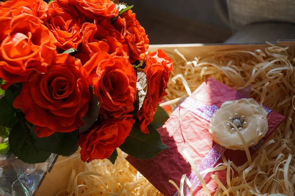 Box with a gift and a bouquet of red roses