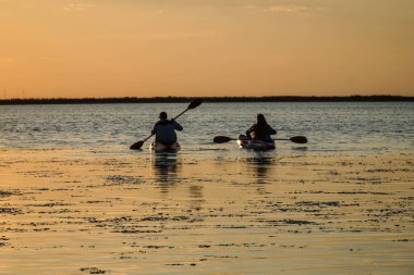 Günbatımı gökyüzünün arka planında iki kano insanı. Azov denizi. Ukrayna.