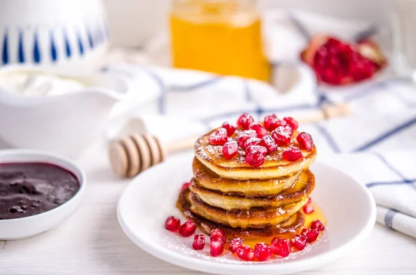 Pancakes with pomegranate seeds, honey and powdered sugar — Stock Photo, Image