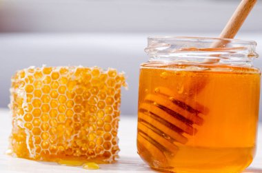 Cam bir kavanozda bal, bal için tahta bir kaşık içinde. Petek