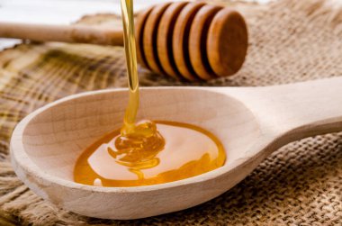 Rustik bir tarzda tahta bir kaşık üzerinde akan taze çiçek bal