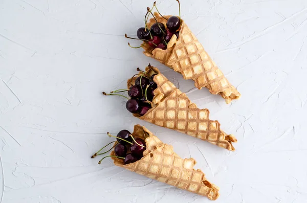 Cono de helado lleno de cerezas en una ba de hormigón blanco claro —  Fotos de Stock