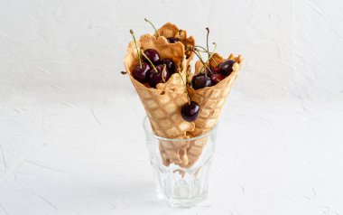 Üç dondurma konileri bir cam beher kiraz ile dolu 