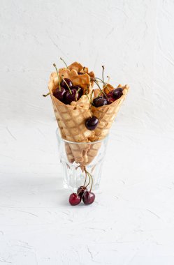 Üç dondurma konileri bir cam beher kiraz ile dolu 
