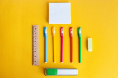 renkli kalemler, ahşap bir cetvel, silgi, zımba, kağıt yanında