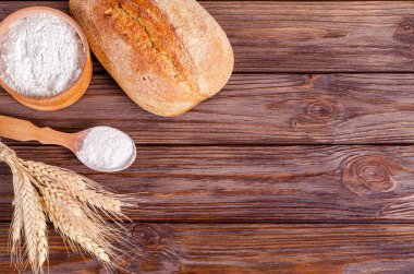 Çavdar ekmeği, un ve ahşap arka planda bir buket çivi. Boşluğu, düzlüğü, metin için yeri kopyala. Yukarıdan görüntüle.
