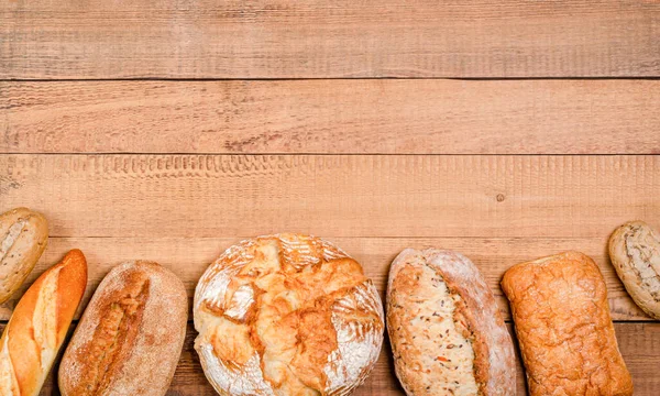 Fırın - çeşitli rustik gevrek somunlar ve tahta tahtalar üzerinde rulo ekmek. Boşluğu, düzlüğü, metin için yeri kopyala. Yukarıdan görüntüle.