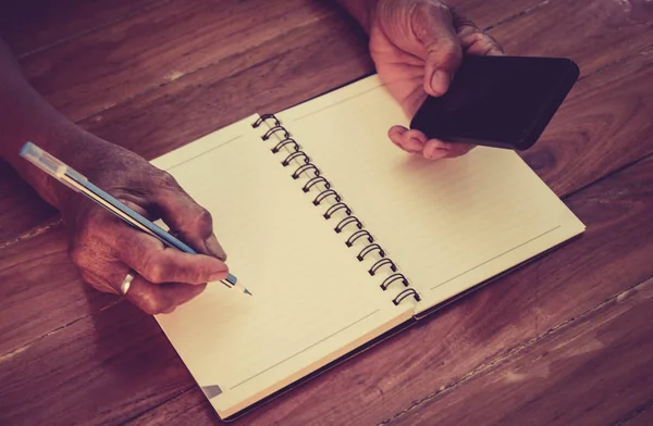 Yaşlı kadının el bir cep telefonu numarası kitapta yazacak. Not alma.