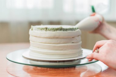 pudra kek üzerine krema sıkar. Kız bir kek yapmak